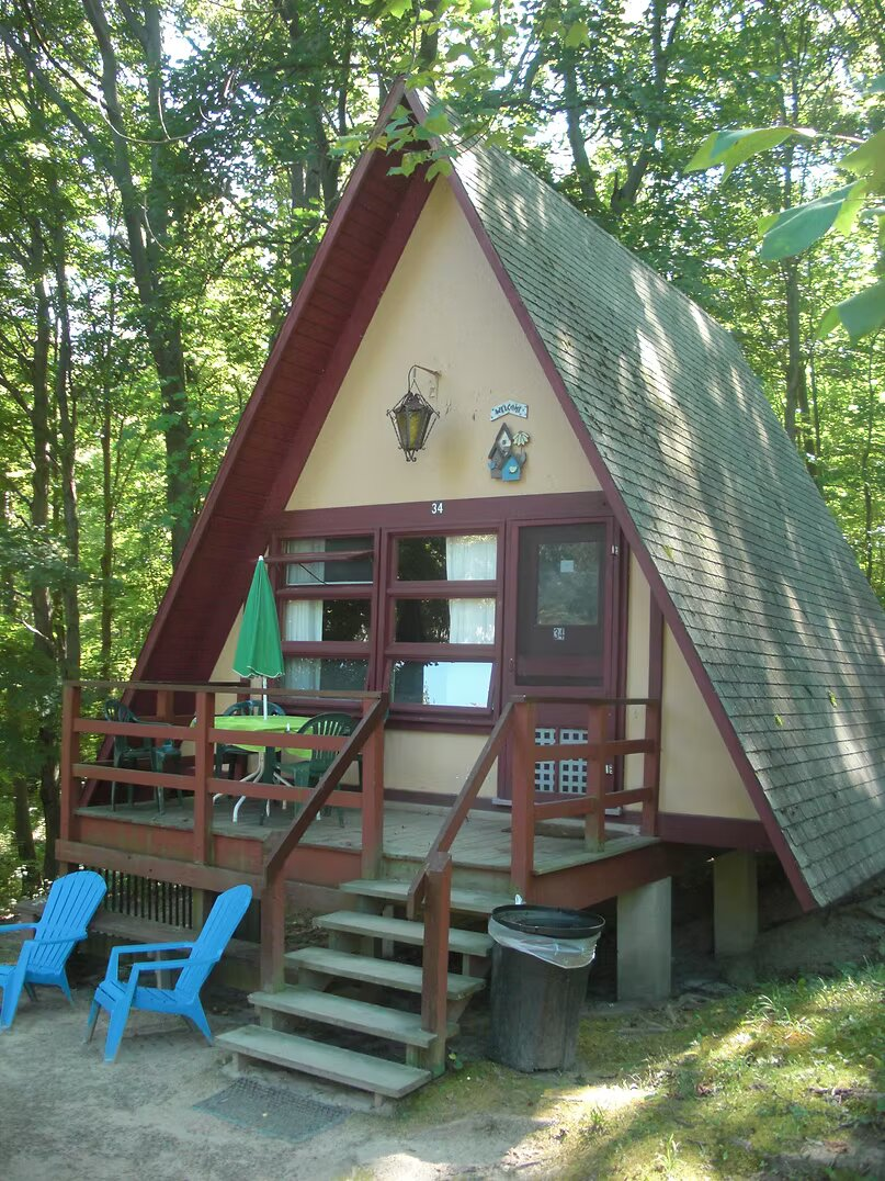Existing A-frame cabin 34 with exposed wood overhang, front porch and asphalt roof
